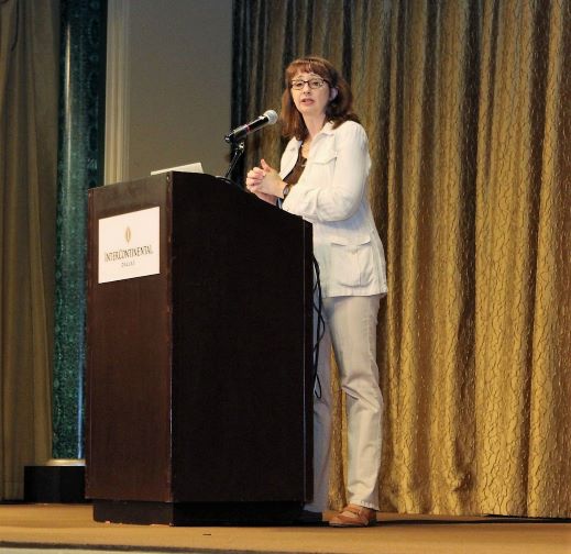 Kathy Dempsey speaking at a podium on a stage